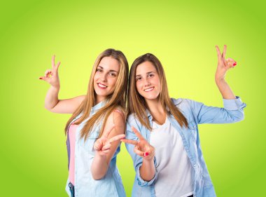 Yeşil arka plan üzerinde zafer jest yapıyor kızlar