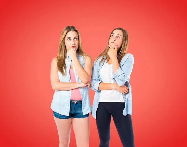 Girls thinking over red background — Stock Photo, Image