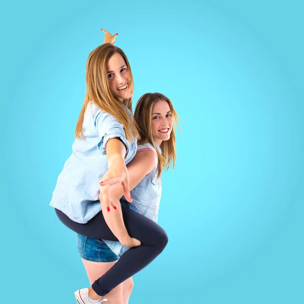 Schwestern spielen vor blauem Hintergrund — Stockfoto