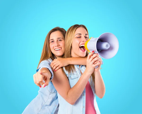 Girls shoutimg with megaphone over blue background — Stock Photo, Image