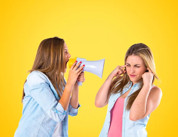 Girl shoutimg with a megaphone at her friend — Stock Photo, Image