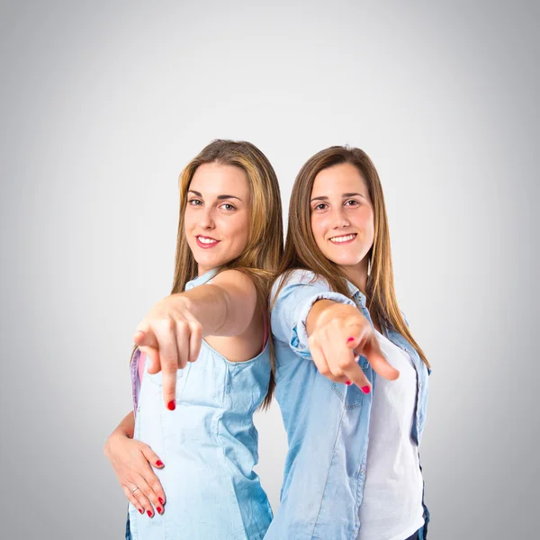 Girls pointing to the front over grey background — Stock Photo, Image