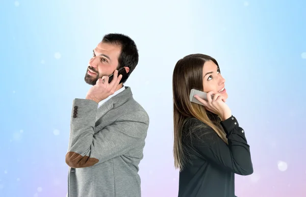 Couple talking to mobile over gloss background. — Stock Photo, Image