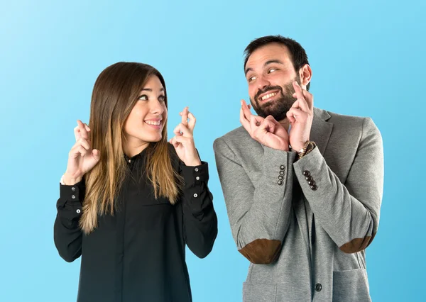 Couple with their fingers crossing over blue — Stock Photo, Image
