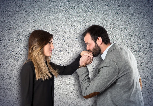 Mann küsst einer Frau die Hand vor strukturiertem Hintergrund — Stockfoto