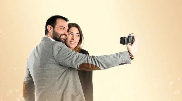 Homem fotografando com sua namorada sobre fundo brilho — Fotografia de Stock