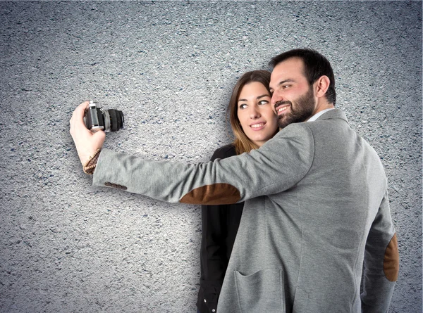 Hombre fotografiando con su novia sobre fondo texturizado — Foto de Stock