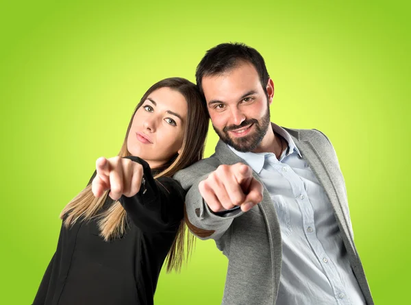 Casal apontando para a frente sobre fundo verde — Fotografia de Stock