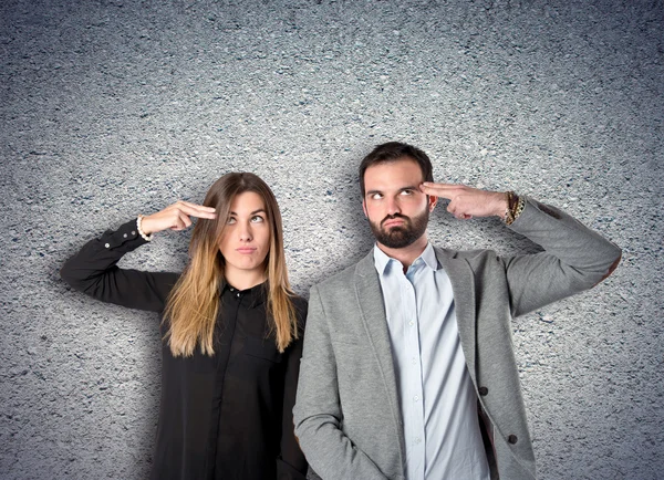 Paar macht Selbstmordgeste vor texturiertem Hintergrund — Stockfoto