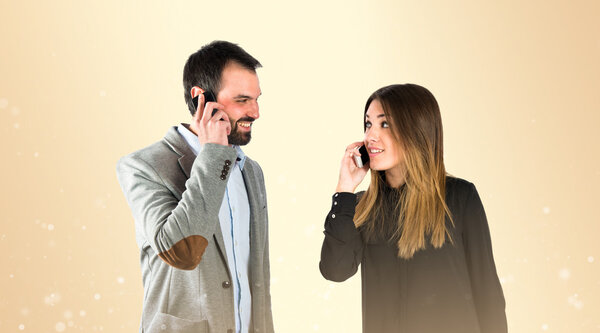 Couple talking to mobile over gloss background. 