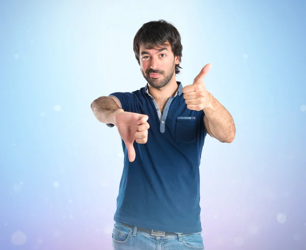 Man doing a bad signal over blue background — Stock Photo, Image