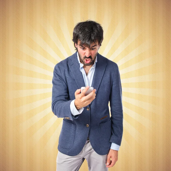 Разгневанный мужчина разговаривает по мобильному телефону на поп-фоне — стоковое фото