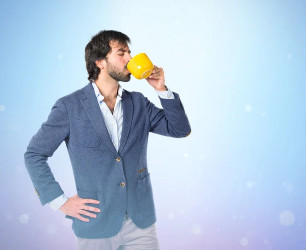 Бизнесмен держит чашку кофе на синем фоне — стоковое фото