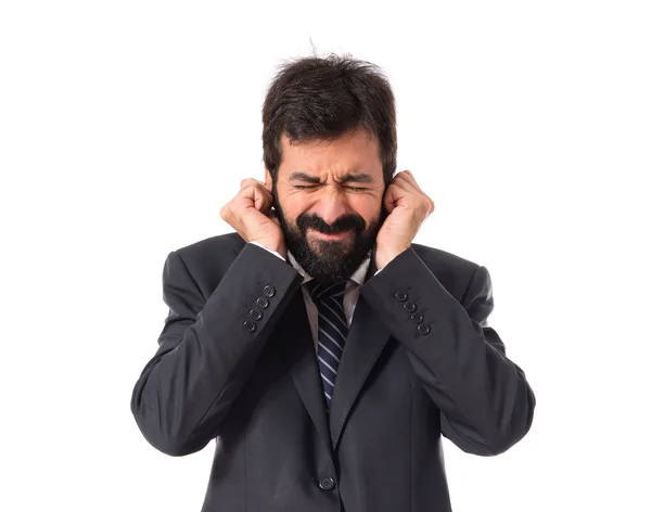 Empresario cubriéndose las orejas sobre fondo blanco — Foto de Stock