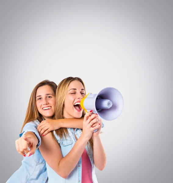 Girls shoutimg with megaphone over grey background — Stock Photo, Image