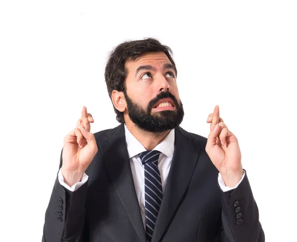 Businessman with his fingers crossing over white background — Stock Photo, Image