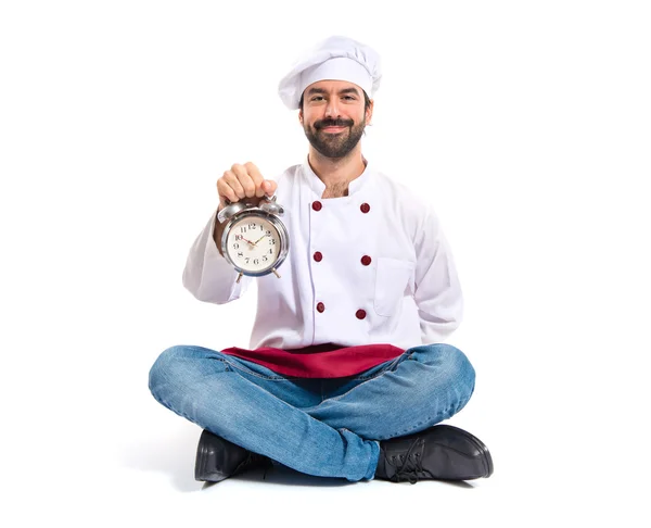 Chef holding a clock over white background — Stock Photo, Image