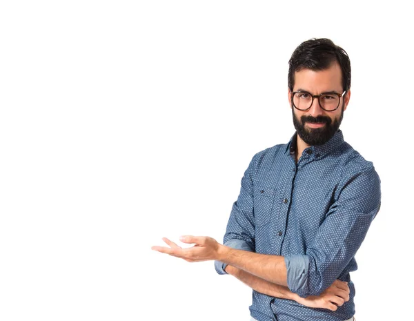 Joven hipster hombre presentando algo sobre fondo blanco — Foto de Stock