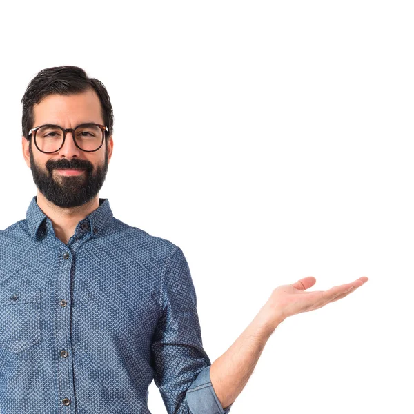 Young hipster man holding something over white background — Stock Photo, Image