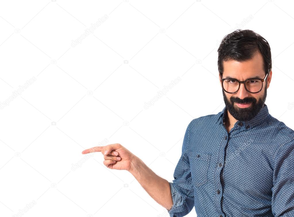 Young hipster man pointing lateral over white background