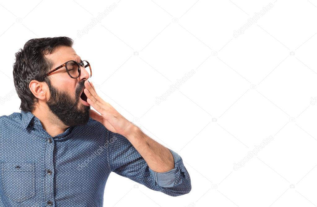 Young hipster man yawning over white background 