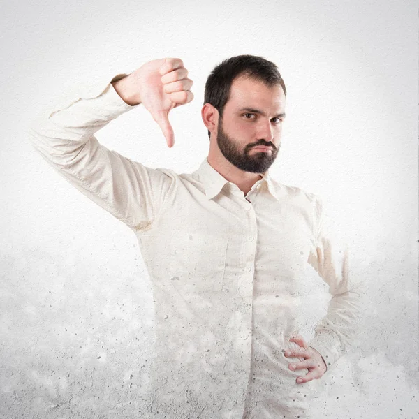 Jonge man met duimen naar beneden op witte achtergrond — Stockfoto