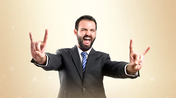 Joven hombre de negocios haciendo el signo de cuerno sobre fondo blanco — Foto de Stock