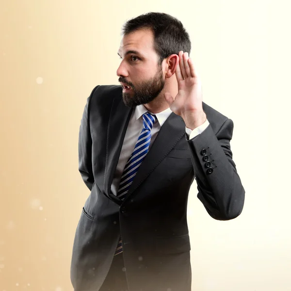 Young business man hearing something over white background — Stock Photo, Image