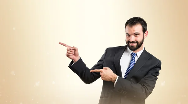 Empresario apuntando hacia un lado sobre fondo blanco — Foto de Stock