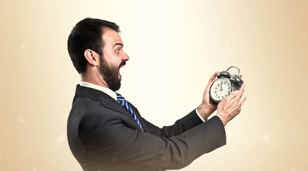 Молодой бизнесмен держит старинные часы на белом фоне — стоковое фото