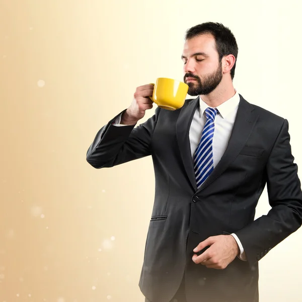 Jonge zakenman drinken een kopje koffie op witte achtergrond — Stockfoto