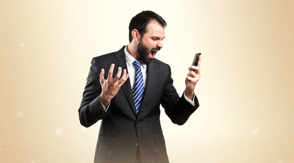 Young businessmen shouting to mobile over isolated background. — Stock Photo, Image