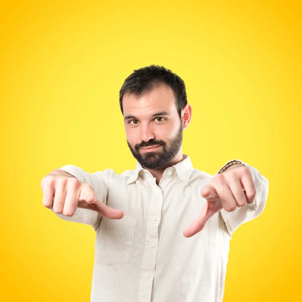 Junger Mann zeigt gegenüber über gelbem Hintergrund — Stockfoto