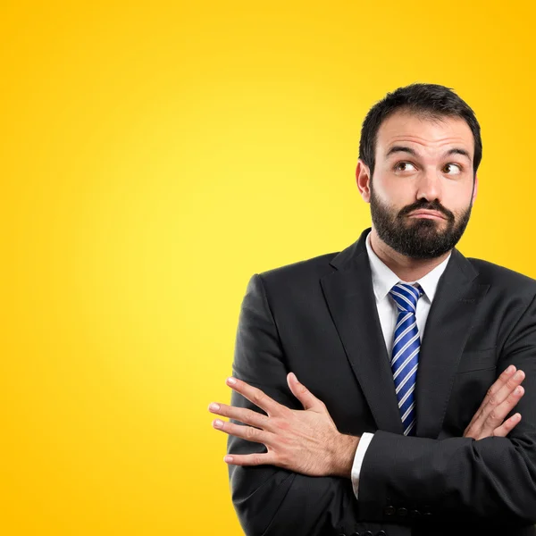 Uomo d'affari con le braccia incrociate su sfondo giallo — Foto Stock