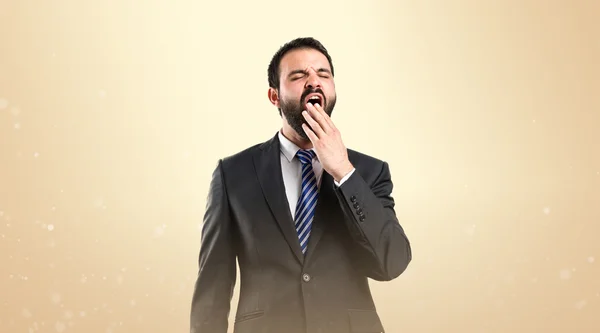 Empresario bostezando sobre fondo ocre — Foto de Stock