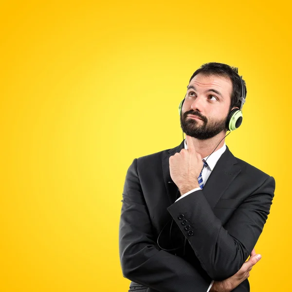 Joven empresario escuchando música sobre fondo amarillo — Foto de Stock