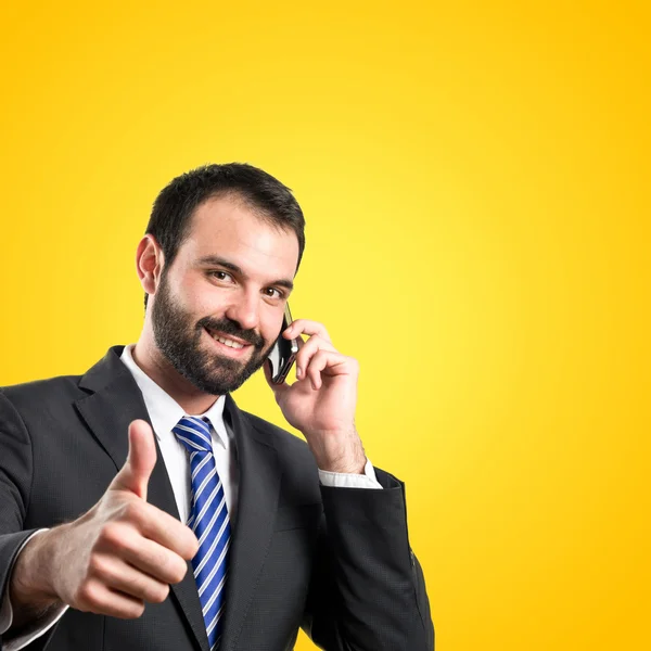 Jovens empresários conversando com celular sobre fundo amarelo . — Fotografia de Stock