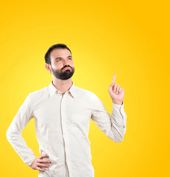 Giovane uomo che punta su sfondo giallo — Foto Stock