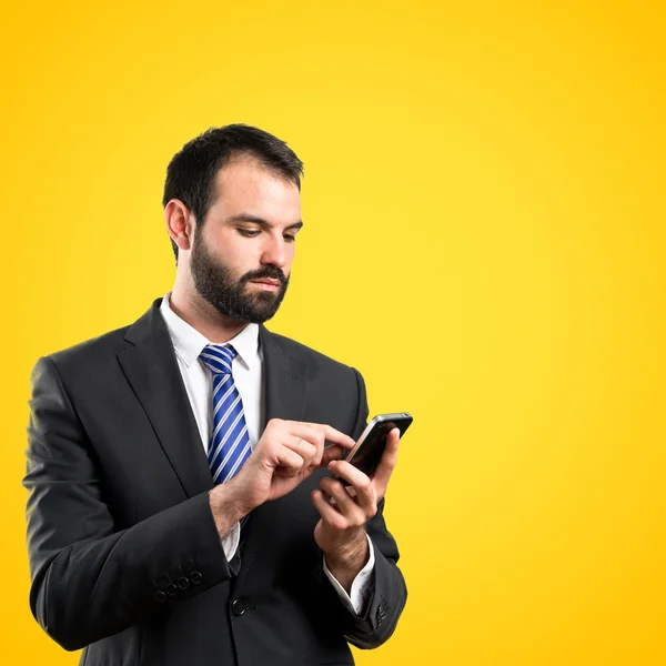 Hombre de negocios enviando un mensaje sobre fondo amarillo . —  Fotos de Stock