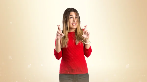 Chica joven cruzando sus dedos sobre fondo blanco —  Fotos de Stock