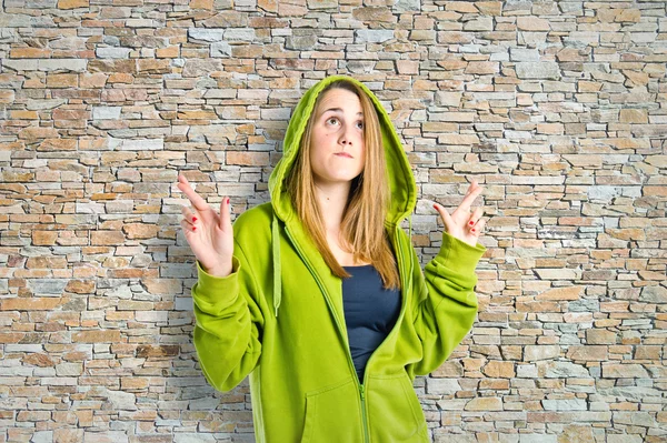 Pretty girl with her fingers crossing over textured background — Stock Photo, Image