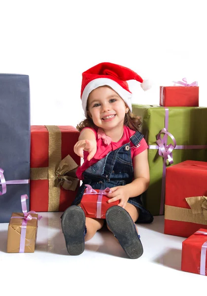 Loira criança natal em torno de vários presentes apontando para o fro — Fotografia de Stock