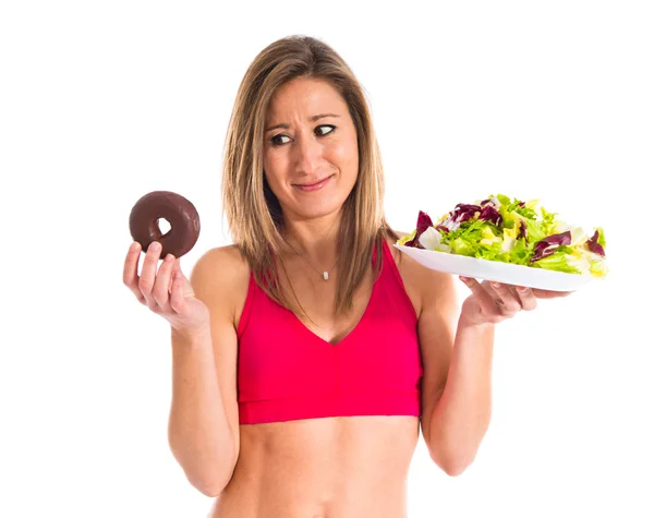 Frau unentschlossen zwischen Donut und Salat — Stockfoto