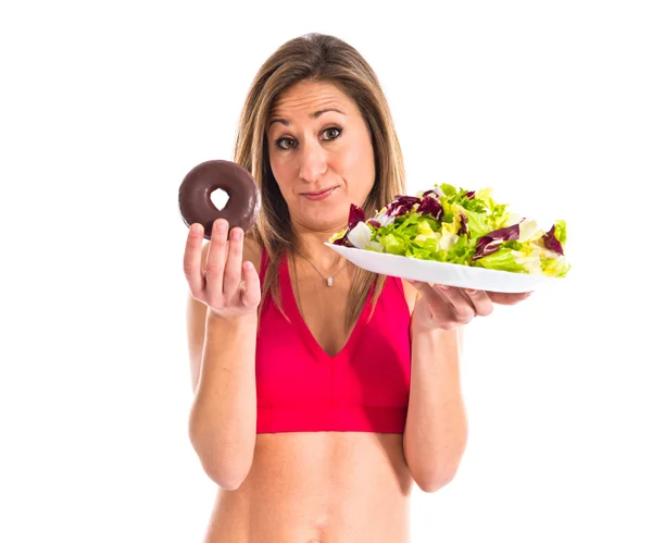 Donna indecisa tra una ciambella e un'insalata — Foto Stock