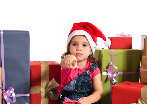 Blonde christmas kid around several presents pointing to the fro Royalty Free Stock Images