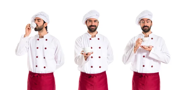 Chef holding a cup of coffee over white background — Stock Photo, Image