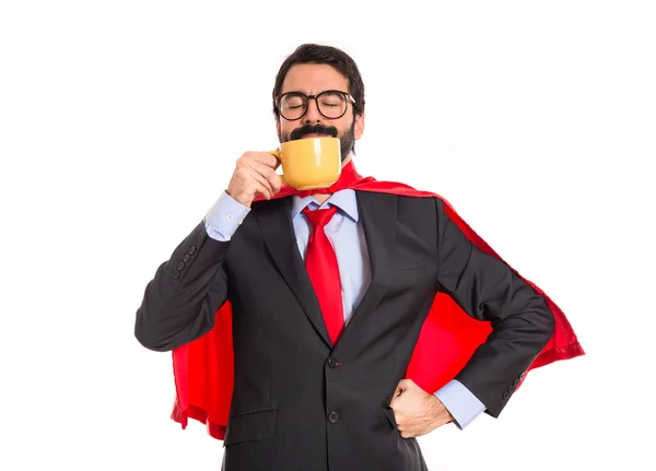 Zakenman gekleed als superheld drinken koffie — Stockfoto