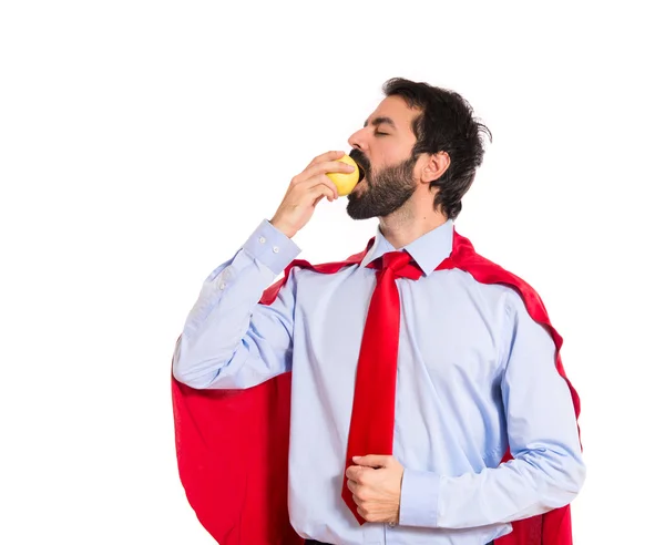 Businessman dressed like superhero eating an apple — Stock Photo, Image