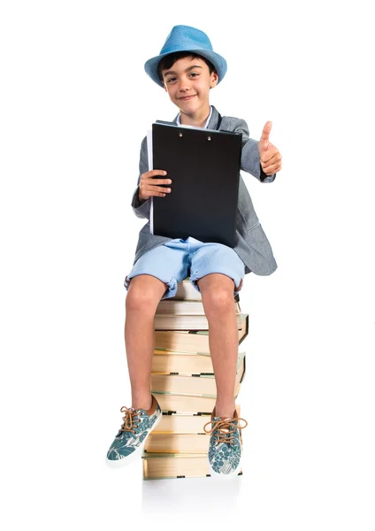 Netter Junge sitzt mit erhobenem Daumen auf Büchern — Stockfoto