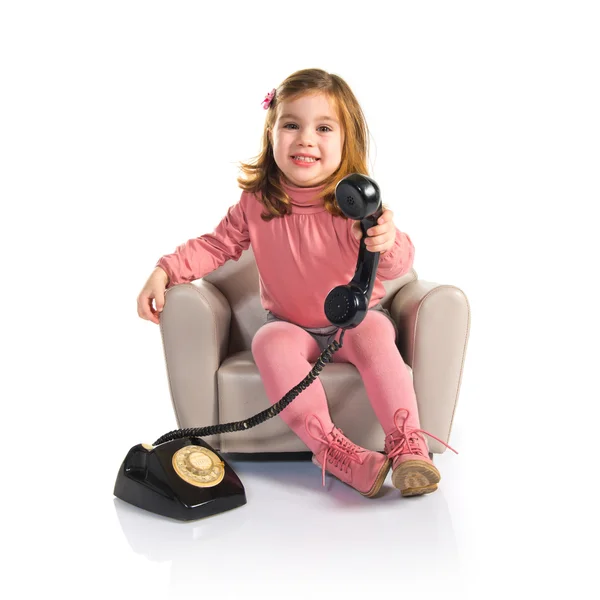 Criança sentada em poltrona conversando com telefone vintage — Fotografia de Stock